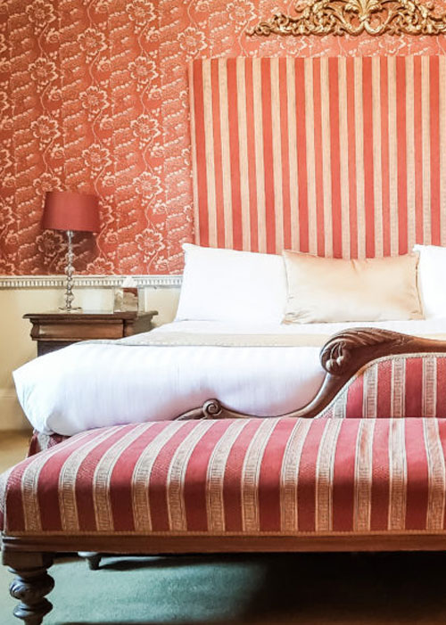 A beautiful bedroom with stripy theme at Colwick Hall Hotel. Queen size bed with long stripy headboard and seat.