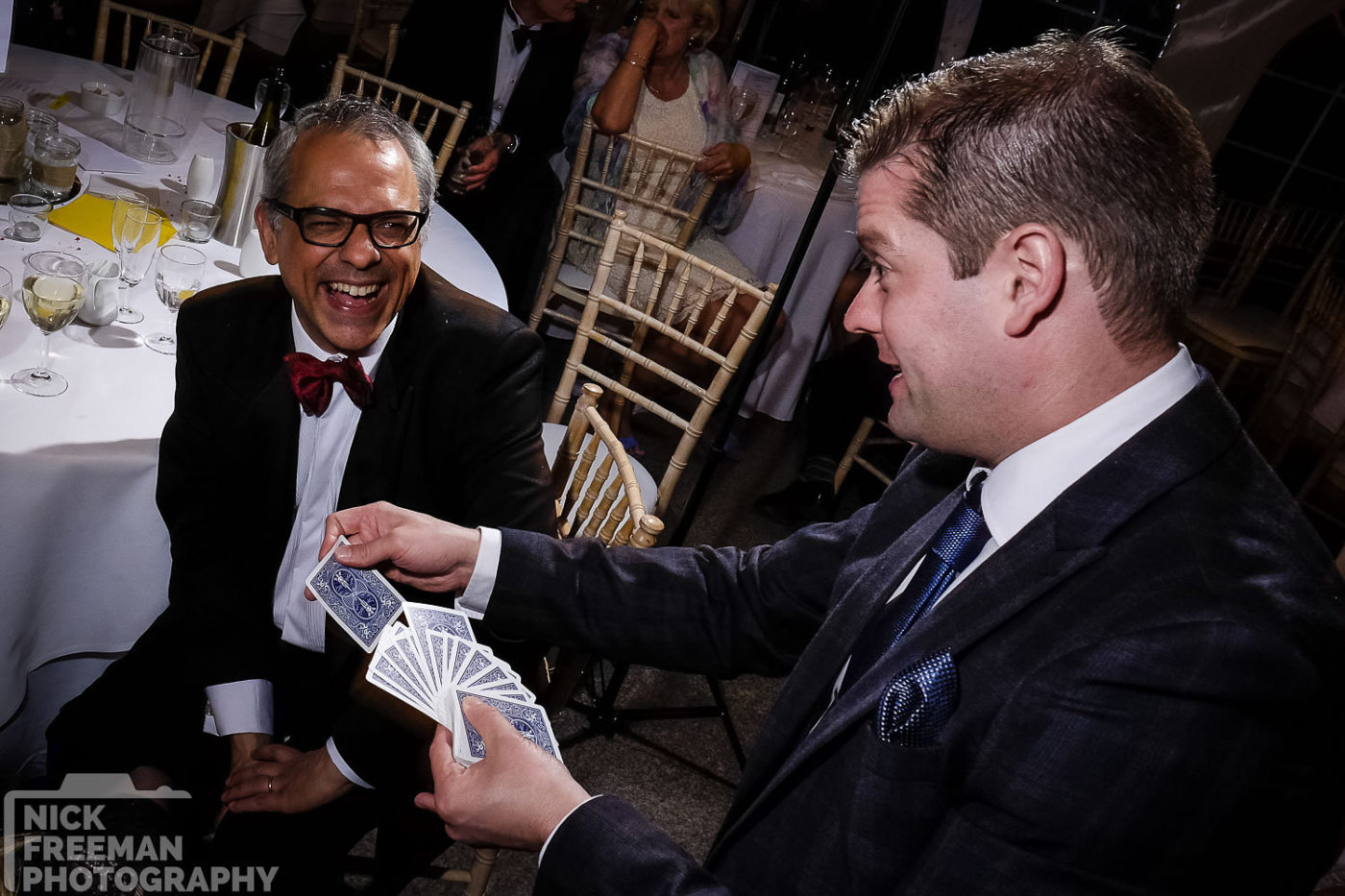 Magician performing to a smiling man.
