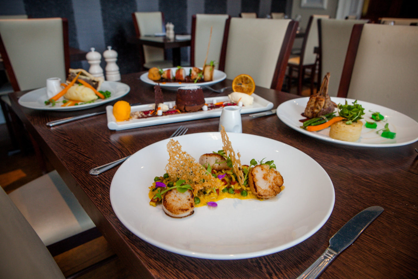 Four dinners served on a table with a chocolate dessert sat in the middle.